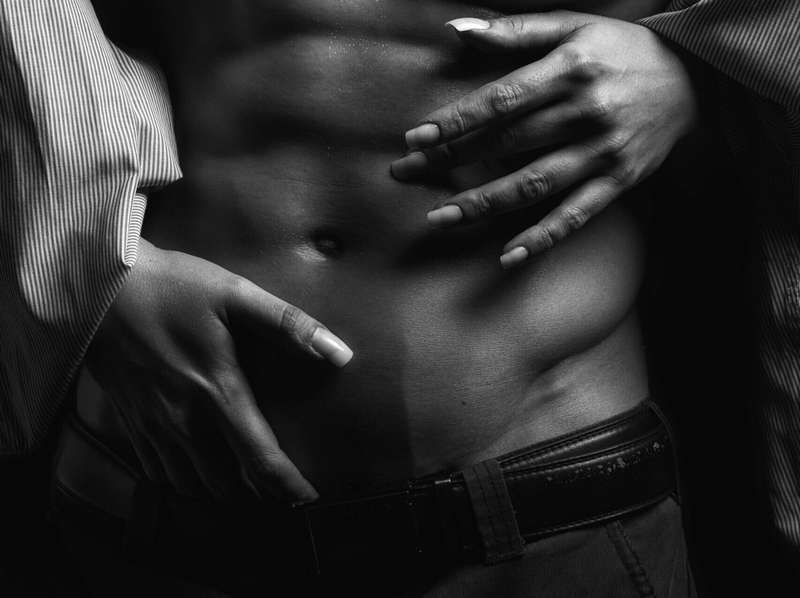 Woman's hands on man's abs going towards groin